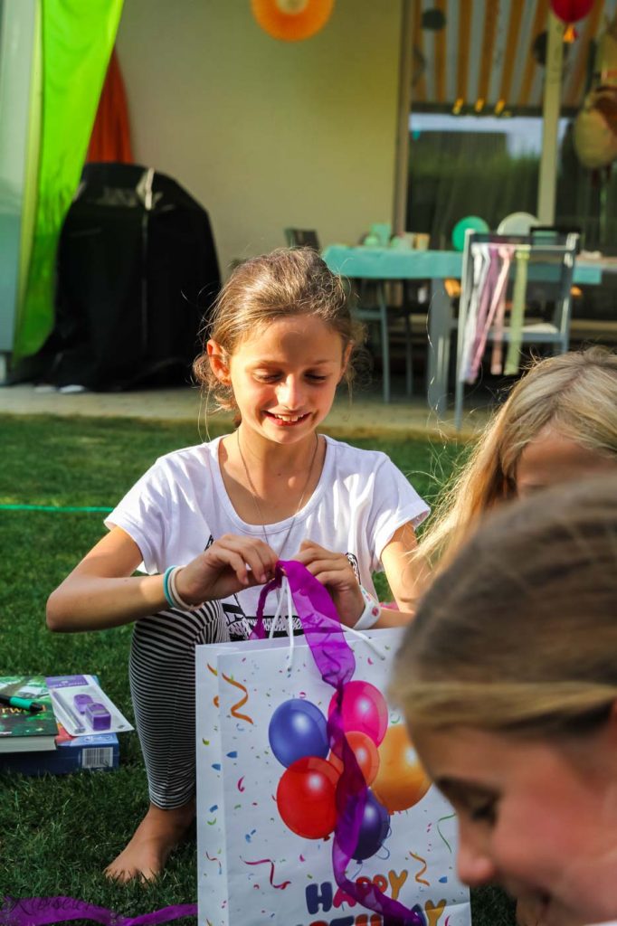 das Geburtstagskind packt ein Geschenk aus