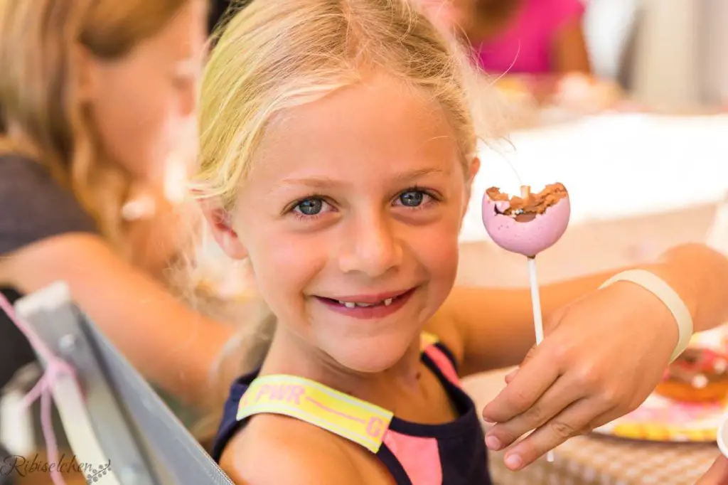 Mädchen lacht mit Donut Cake Pop in der Hand
