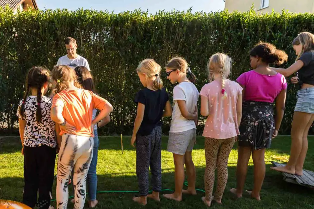 Kinder stehen aufgereiht vor einer Linie beim Partyspiel Donut werfen