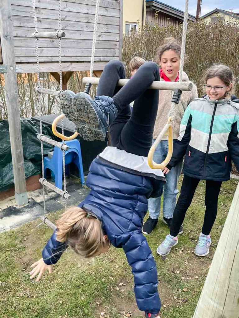 Kind hängt mit den Beinen am Trapez