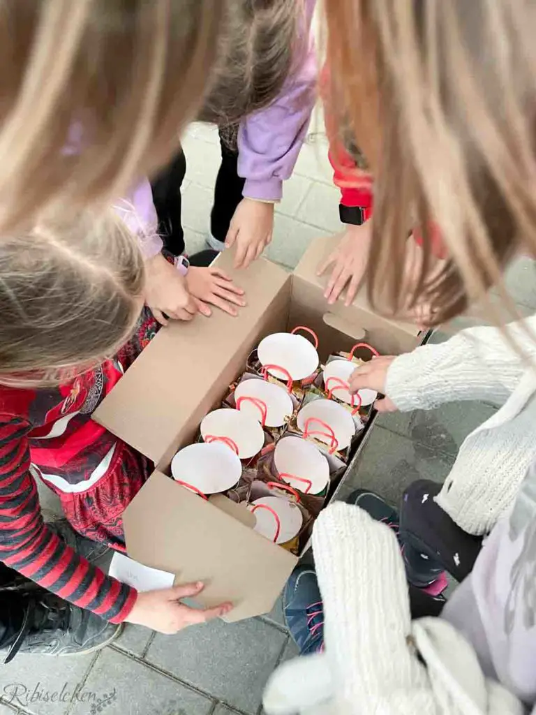 Kinder öffnen eine Schachtel, in der sich Geschenktüten befinden