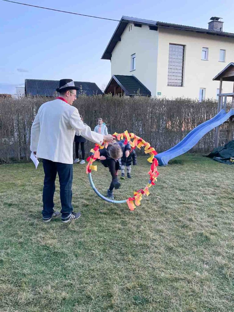 Zirkusdirektor hält den Reifen und Kind springt durch