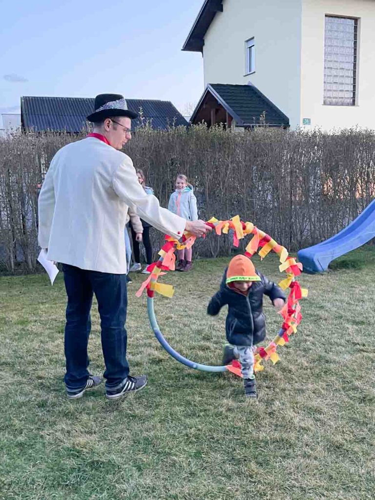 Zirkusdirektor hält den Hula Hoop Reifen und Kind springt durch